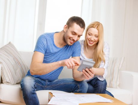 smiling couple with papers and calculator at home